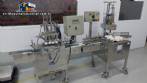 Linear filling machine with 4 stainless steel screw-on nozzles for bottles.