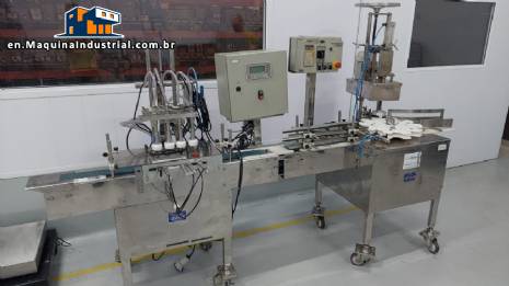 Linear filling machine with 4 stainless steel screw-on nozzles for bottles.